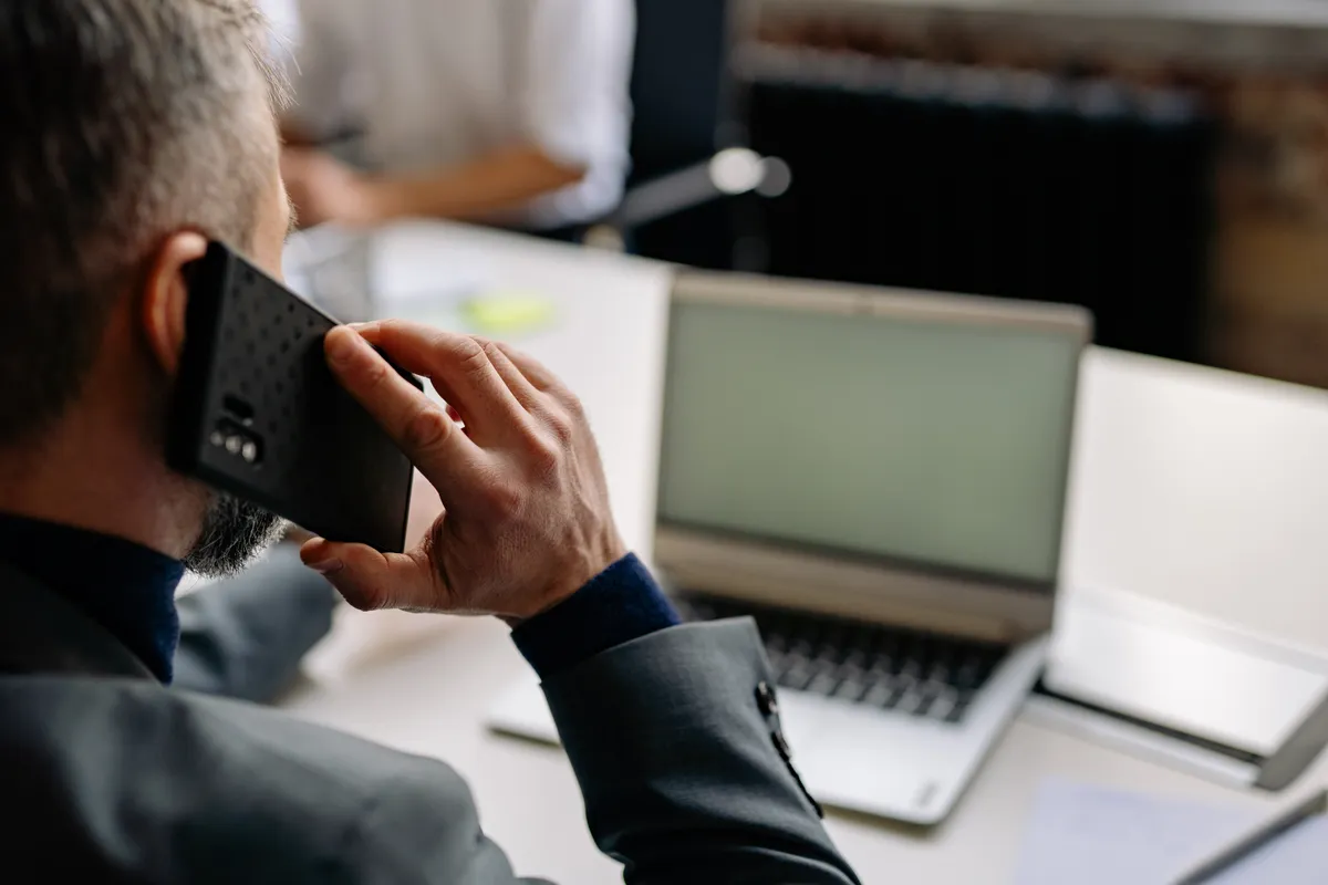 A job seeker taking a recruiter call while working at a laptop