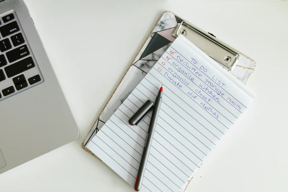 A checklist being ticked off on a clipboard next to a laptop
